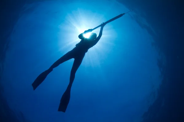 En silhuett av en ung kvinna spearfishing — Stockfoto