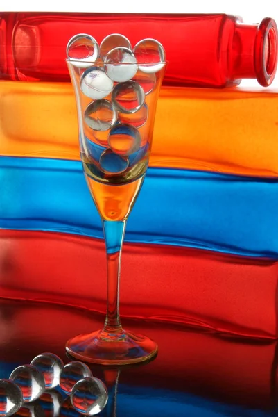 Glass balls in glass and multicolor decorative bottles as background — Stock Photo, Image