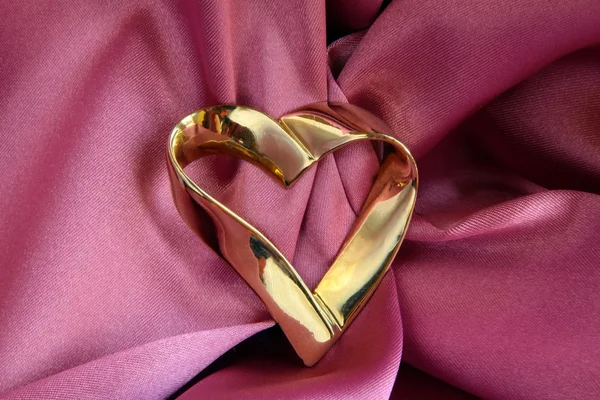 Zlaté srdce broche na růžové saténové — Stock fotografie