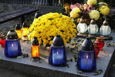 Tomb in cemetery with flowers and burning candles clipart