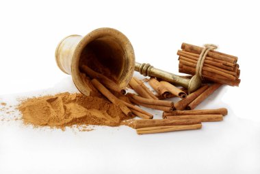 Cinnamon stics and powder grinded in montar clipart