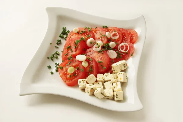 Салат с сыром, ломтиками помидоров и зеленой заточкой — стоковое фото