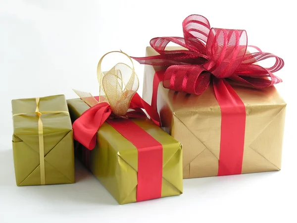 De giften van Kerstmis in gold papier en decoratieve rode linten — Stockfoto