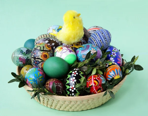Osterdekoration mit gelben Hühnchen und bemalten Eiern im Korb — Stockfoto
