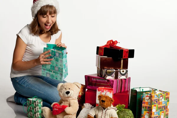 Smiling christmas girl unpacking gifts. Isolated on white. — Stock Photo, Image