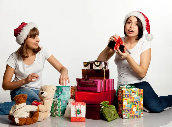 Zwei lächelnde Weihnachtsmädchen beim Auspacken der Geschenke lizenzfreie Stockbilder