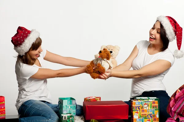 Zwei lächelnde Weihnachtsmädchen beim Auspacken der Geschenke Stockfoto