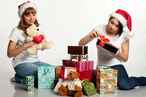 Zwei lächelnde Weihnachtsmädchen beim Auspacken der Geschenke lizenzfreie Stockfotos