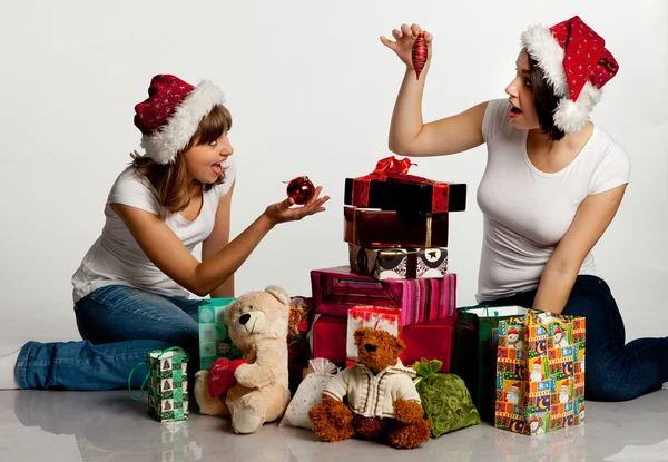 Zwei lächelnde Weihnachtsmädchen beim Auspacken der Geschenke Stockbild