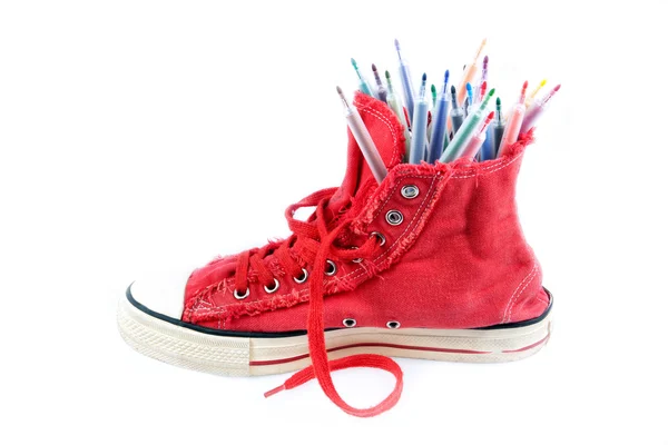 Spor ayakkabı, beyaz bir arka plan olarak renkli kalemler. — Stok fotoğraf