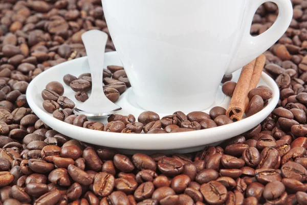 Koffiekopje met kaneel in koffie bonen. — Stockfoto