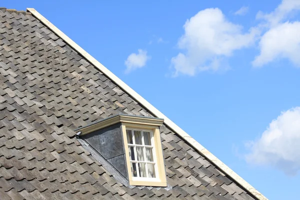 Taket med ett fönster och en blå himmel Stockbild