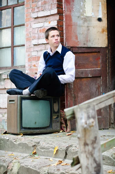 Young man is sitting near old house — Stock Photo, Image