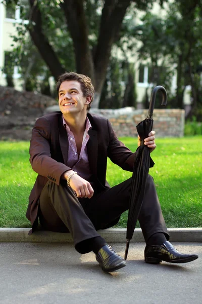Usmívající se muž sedící v trávě — Stock fotografie