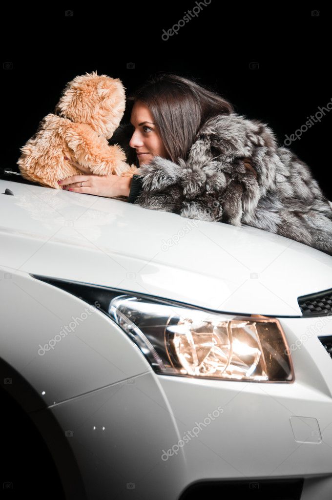 Girl laying on car hood with plush toy