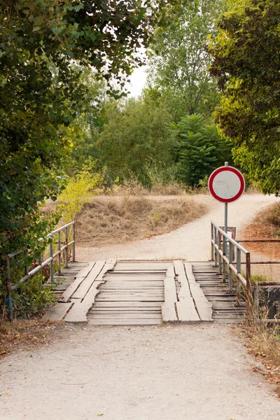 Wooden bridge against trees and falling leaves and no way sign — Stock Photo, Image