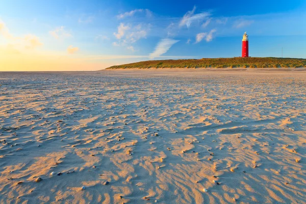 Seaside with sand dunes and lighthouse at sunset — Stock Photo, Image