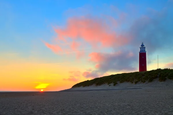 Strand met zandduinen en vuurtoren bij zonsondergang — Stockfoto