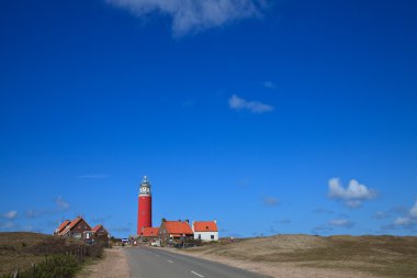 Lighthouse in the dunes at the beach clipart