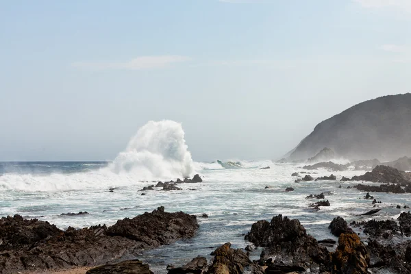 Висока хвиля, що ламається на скелях — стокове фото