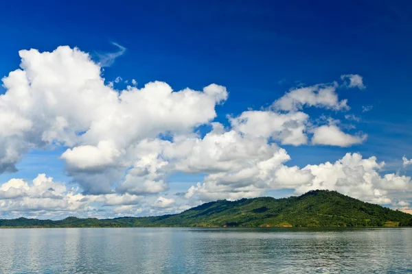 Grandes nuvens brancas acima de um lago e montanhas — Fotografia de Stock