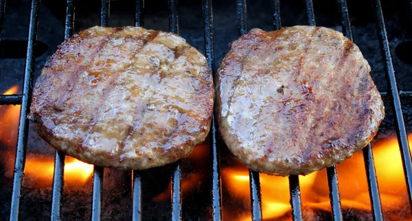 Two juicy burgers sizzling on the grill — Stok fotoğraf