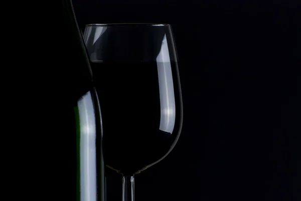 Bottiglia e bicchiere di vino rosso isolato su sfondo nero — Foto Stock