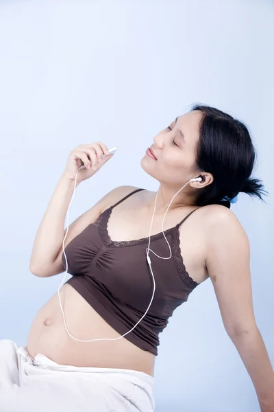 怀孕的女人听音乐 — 图库照片