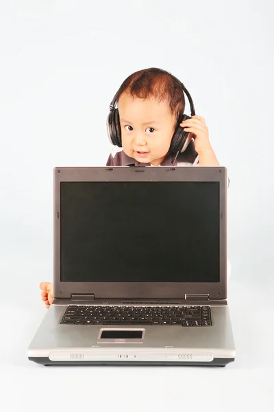 Criança bonito com laptop e fone de ouvido — Fotografia de Stock