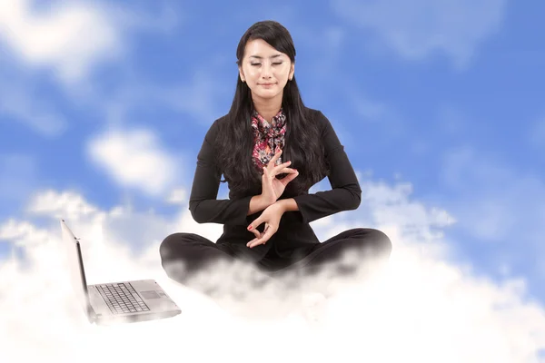 Attractive business woman meditating above the clouds — Stock Photo, Image