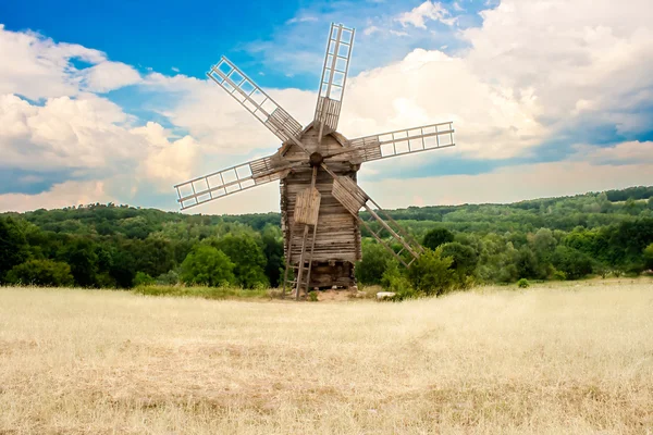 stock image Wooden windmills on green field