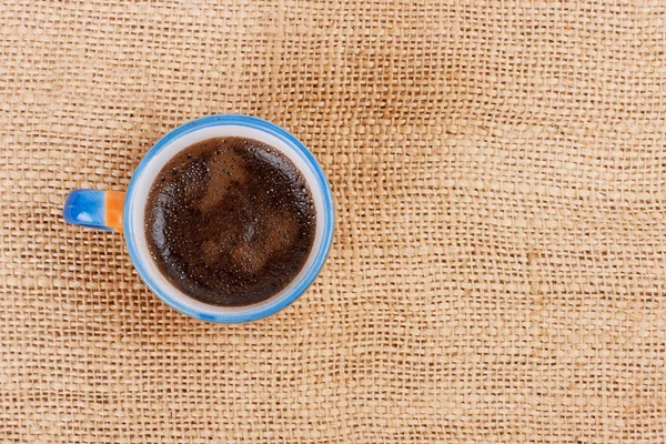 Xícara de café em pé sobre pano de saco — Fotografia de Stock
