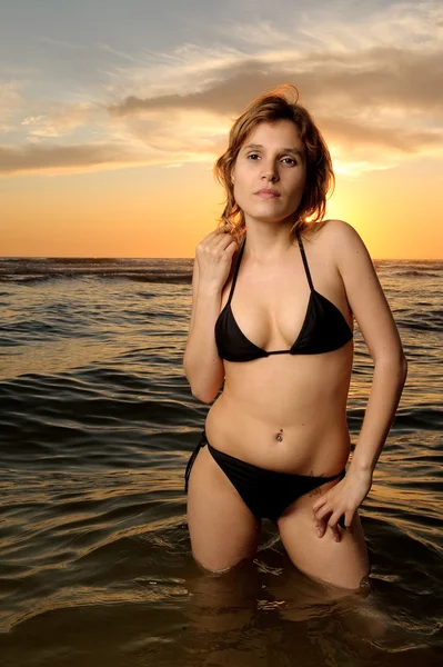 Mooie blonde model in zwarte bikini op het strand — Stockfoto