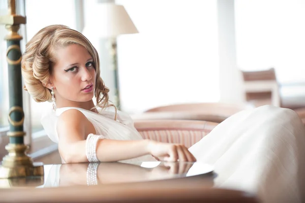 Unga bruden i vit klänning sitter — Stockfoto