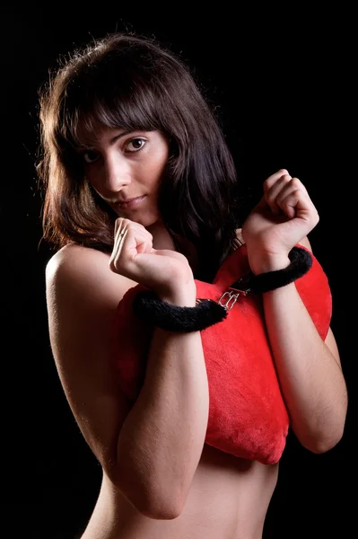 Чуттєва жінка в наручниках тримає подушку у формі серця — стокове фото