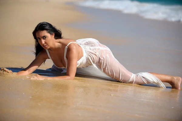 Mujer morena tumbada en la arena en la playa —  Fotos de Stock