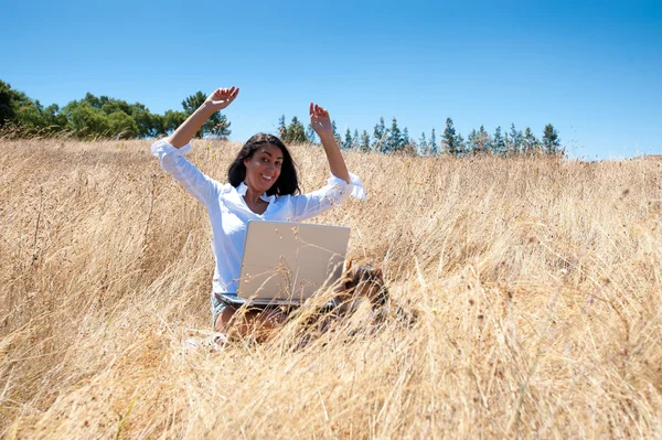 Frau mit Laptop auf einem Feld — Stockfoto