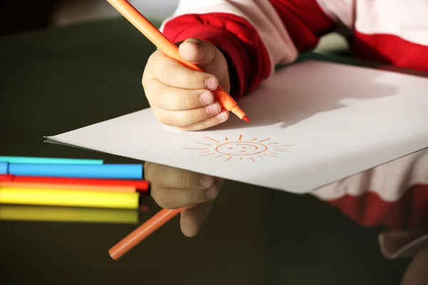 Niño dibujando un sol con marcadores de colores cerca de las manos — Foto de Stock