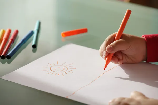 Enfant dessinant un soleil avec des marqueurs colorés fermer les mains — Photo