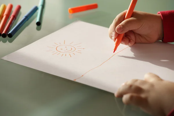 Criança que desenha um sol com marcadores coloridos fecham mãos — Fotografia de Stock