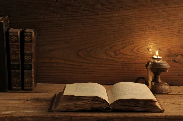 Stará kniha na dřevěný stůl při svíčkách — Stock fotografie