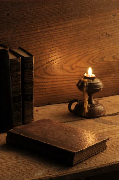 Livro velho em uma mesa de madeira à luz de velas — Fotografia de Stock
