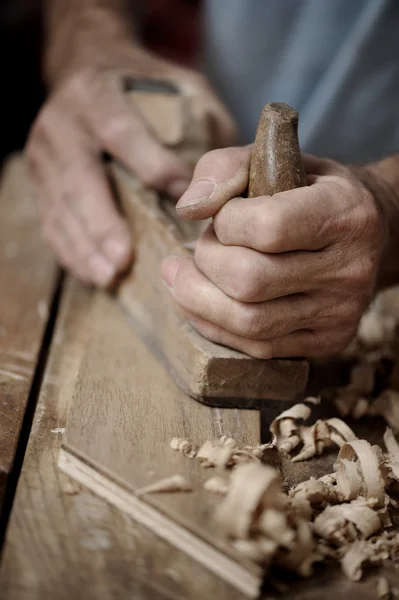 Manos de hombre con plano de carpintero sobre fondo de madera — Foto de Stock