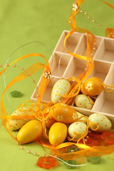 Huevos de Pascua amarillos con caja, flores y cinta — Foto de Stock