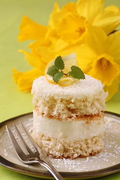 Coconut and lemon cake with daffodils — Stock Photo, Image