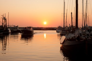 Sunset in Dutch harbor with sailing boats clipart