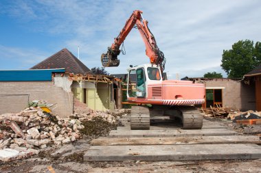 Destruction of a building by a caterpillar crane clipart