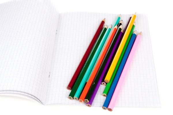 Livro de exercícios com lápis coloridos isolados sobre branco — Fotografia de Stock