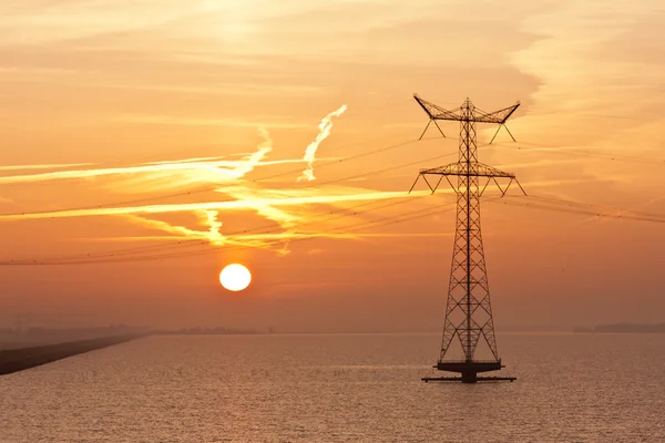 Nascer do sol sobre o mar holandês com um pilão de eletricidade — Fotografia de Stock