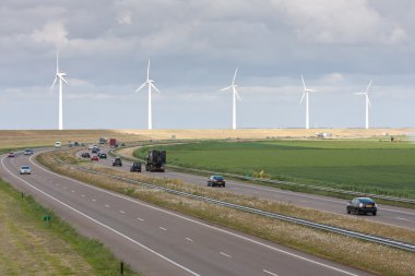 Motorway with a line of big windturbines behind it clipart